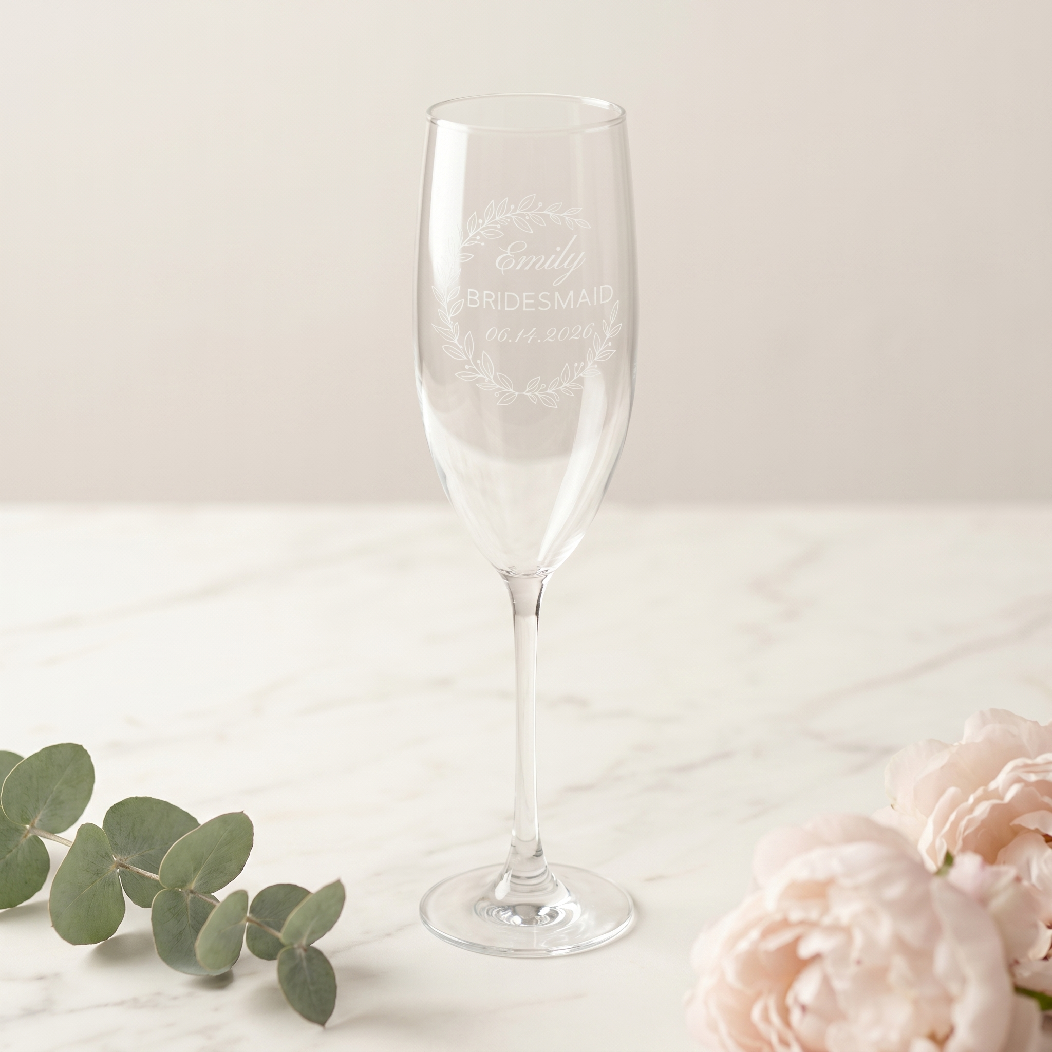 A personalized Eucalyptus Crescent Crest champagne flute resting in a kraft proposal box with a handwritten will-you-be-my-bridesmaid card and silk ribbon.
