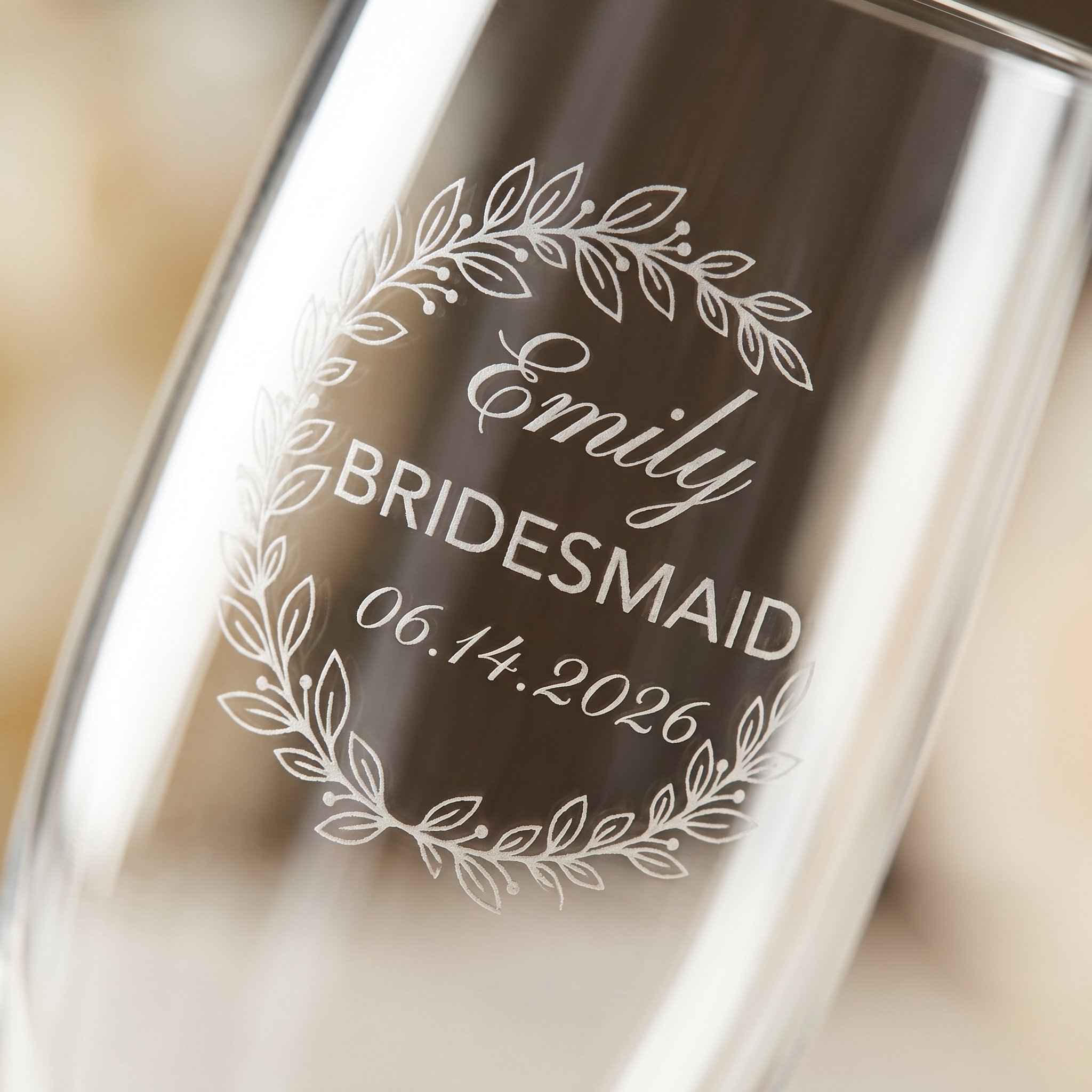 Macro closeup of the Eucalyptus Crescent Crest engraving on a champagne flute — a soft half-moon arch of silver dollar and seeded eucalyptus above a cursive first name, the word 'Bridesmaid' in small caps, and a wedding date in italic script.